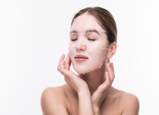 Koreańskie maseczki w płachcie – hit czy kit? Dbanie o skórę od młodości pozwoli nam przesunąć czas powstawania zmarszczek. Na zdjęciu kobieta nakłada maseczkę w płachcie na twarz.