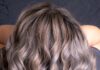 Różne rodzeje włosów potrzebują różnej pielęgnacji. Na zjęciu kobieta prezentuje swoje długie, kręcone farbowane na szaro włosy.